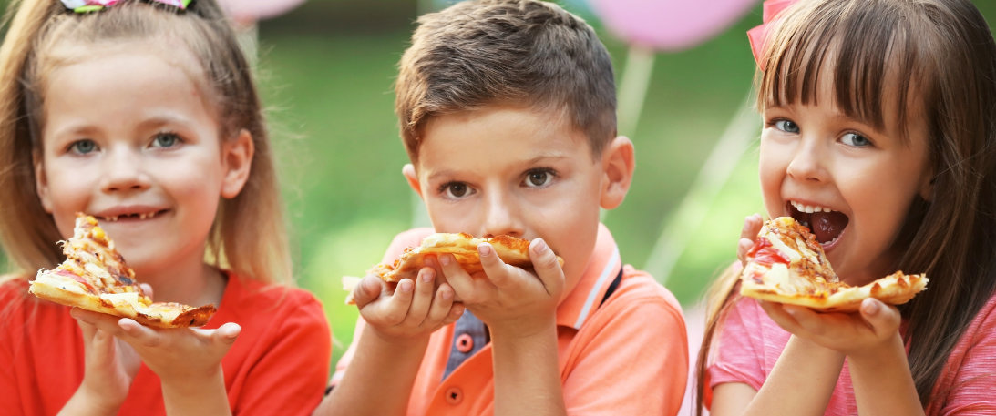 Three kids, each of which are eating a slice of delicious pizza